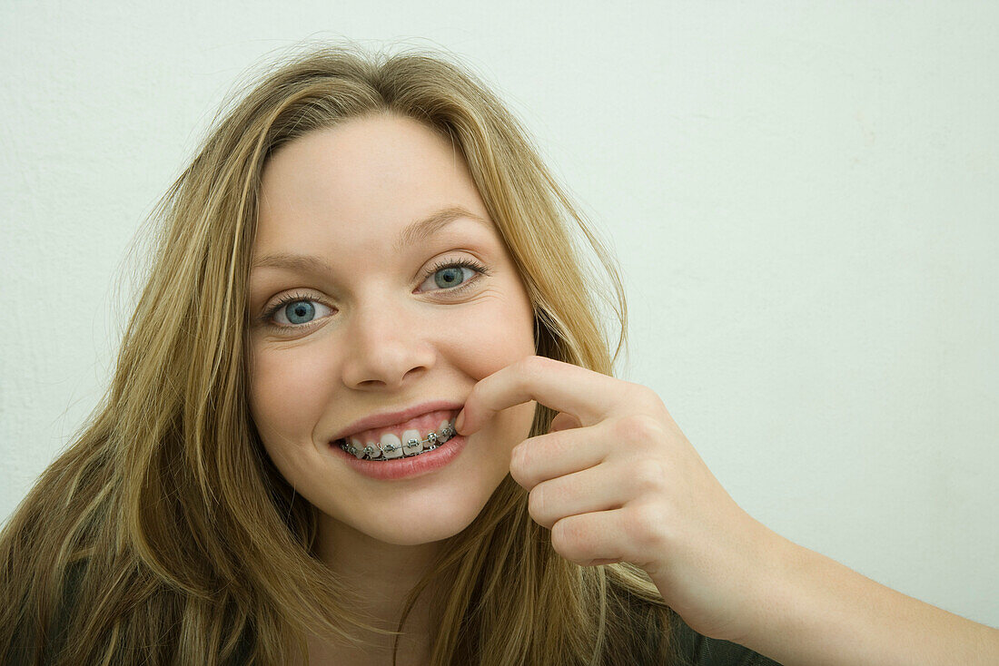Teen girl with braces picking teeth with finger