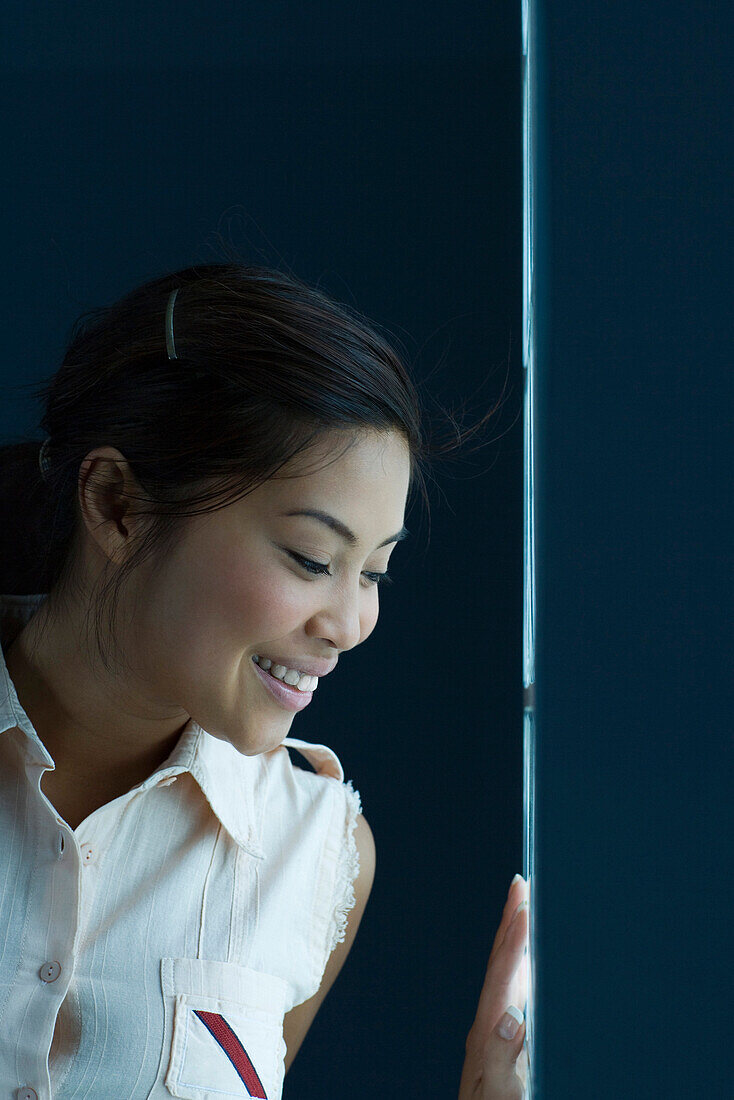Woman looking out narrow window, smiling