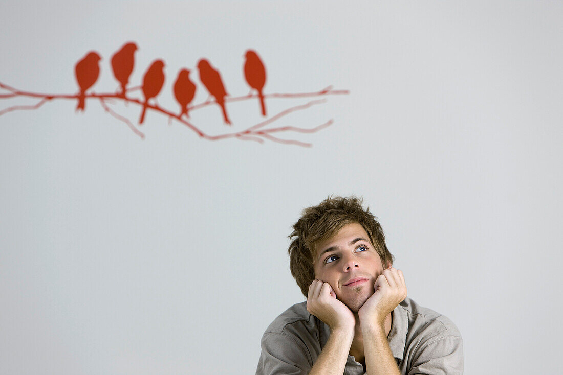 Young man daydreaming, chin resting on hands