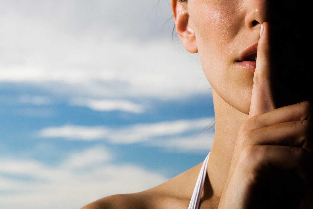 Woman holding finger on lips in silent gesture, cropped