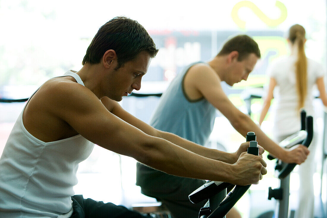 Men on exercise bikes in gym