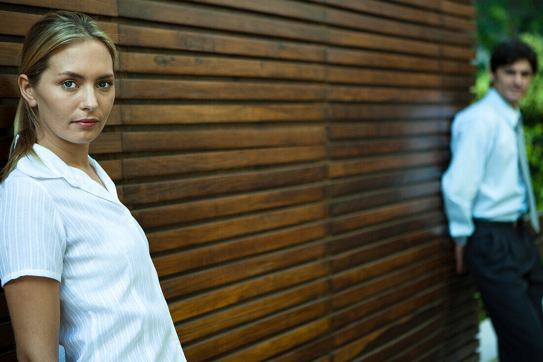 Couple leaning against wall with several feet of space between them