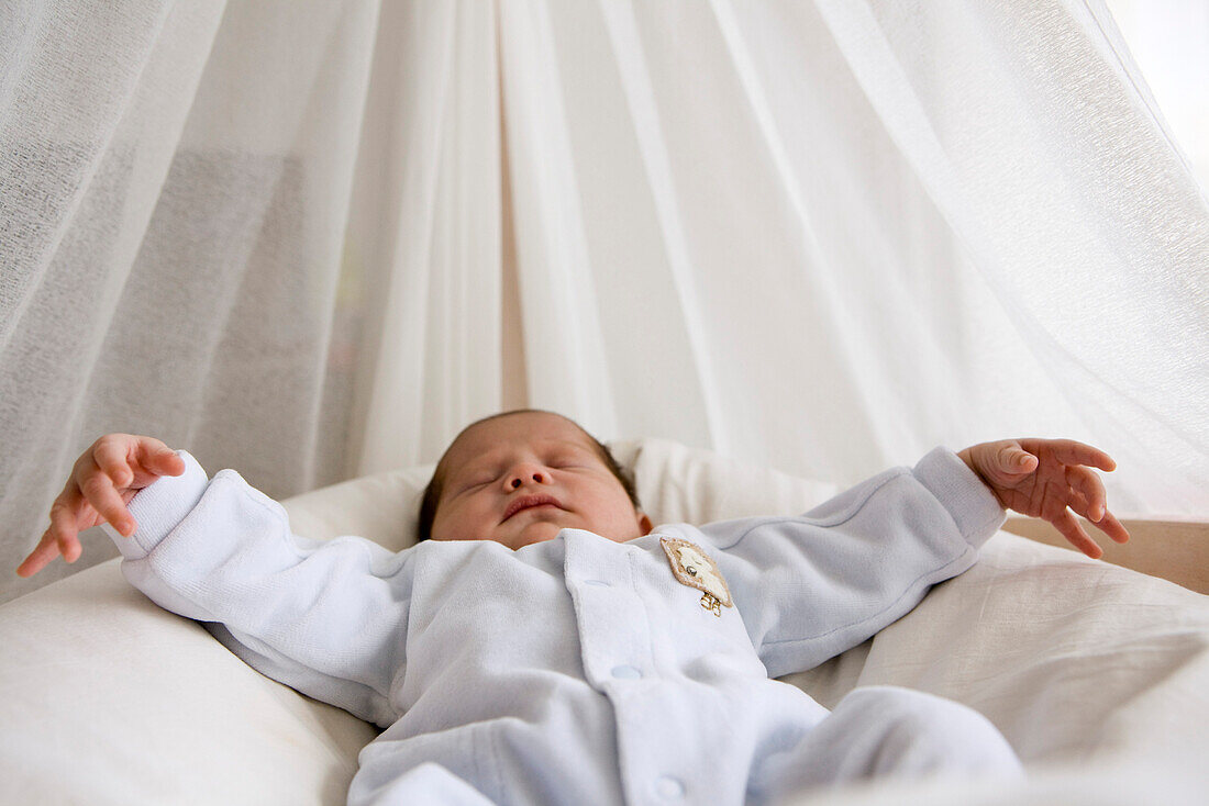 Baby sleeping in crib with arms out