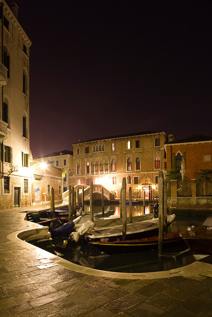 Italy, Venice, gondolas docked along canal at night