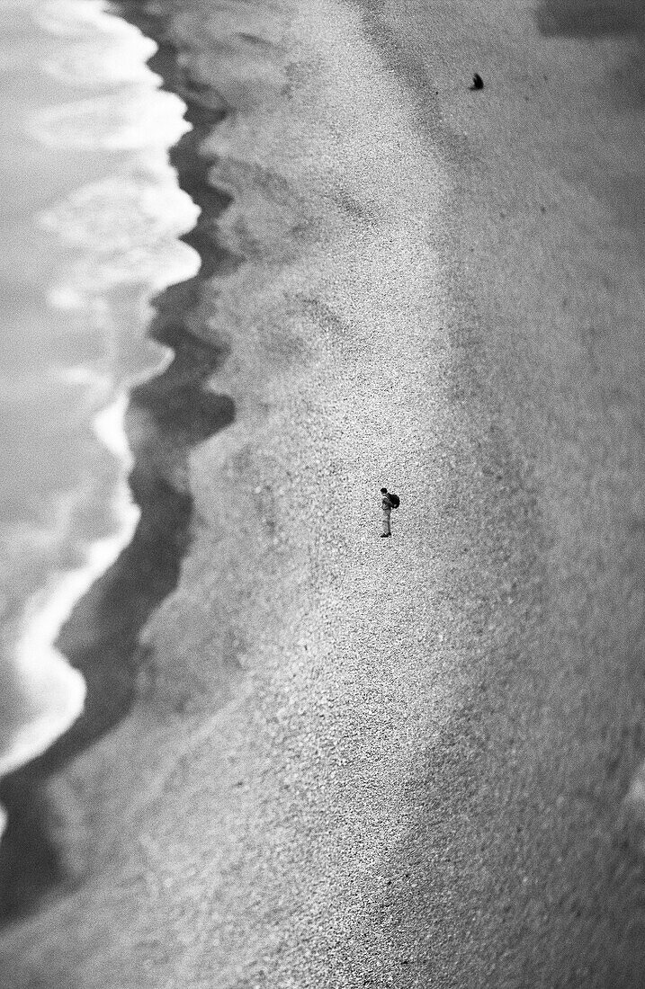 Person standing on beach, aerial view, b&w