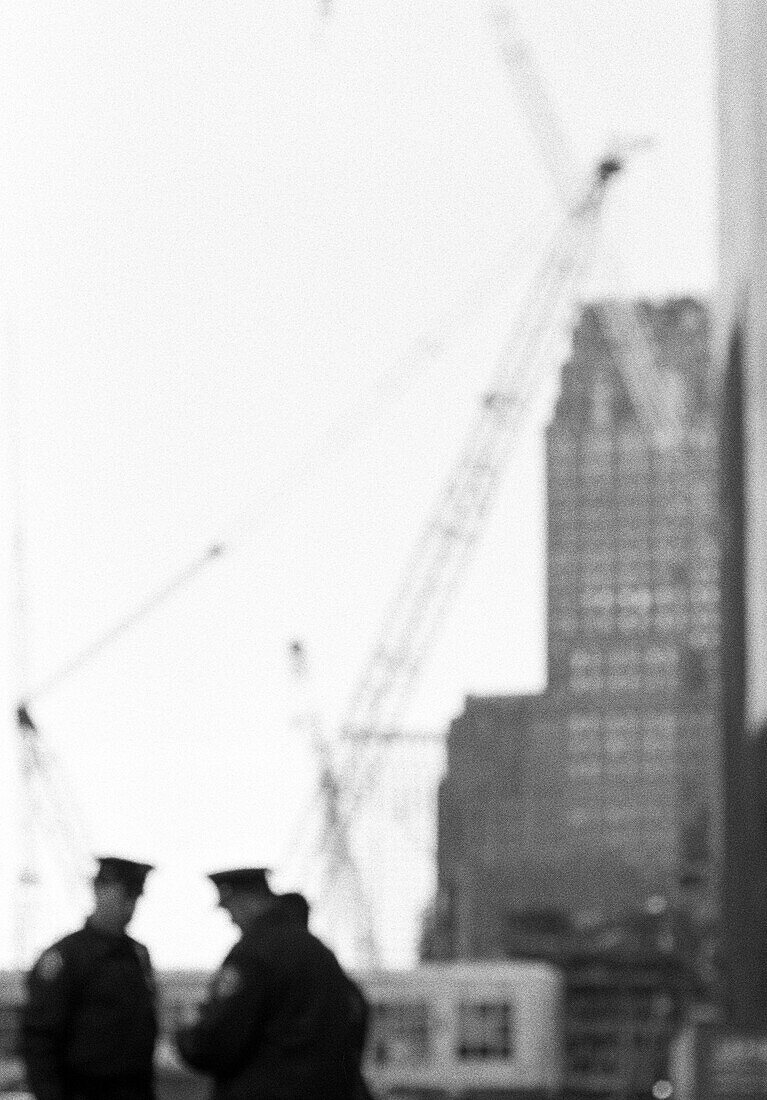 Police officers in front of skyscraper and cranes