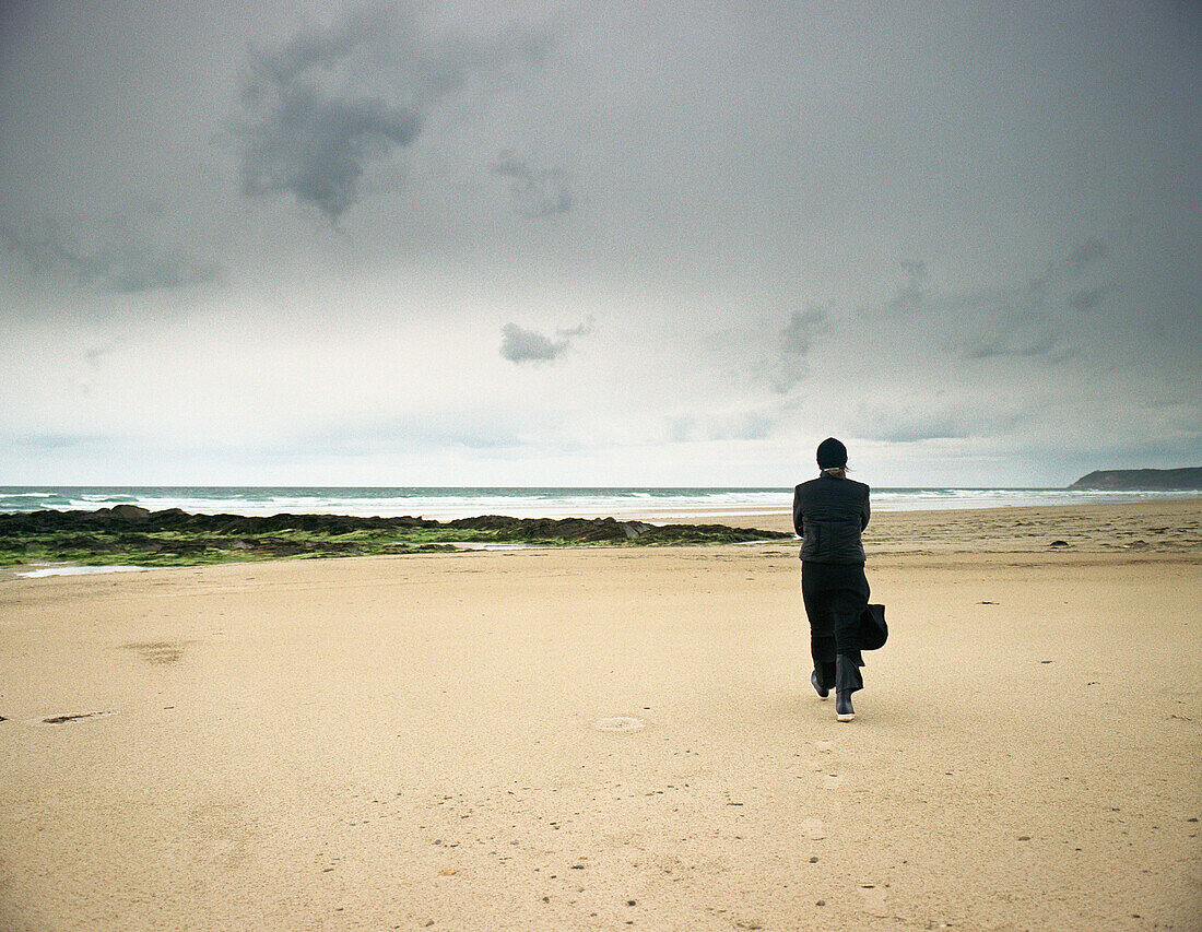 Person walking on beach, rear view