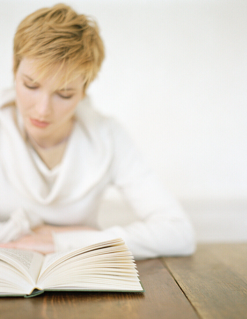 Woman sitting at table reading book