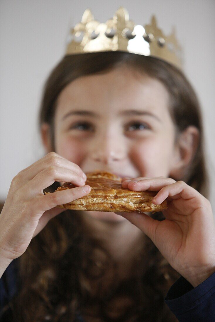 France, Girl eating Galette des rois, French pastry eaten on Epiphany