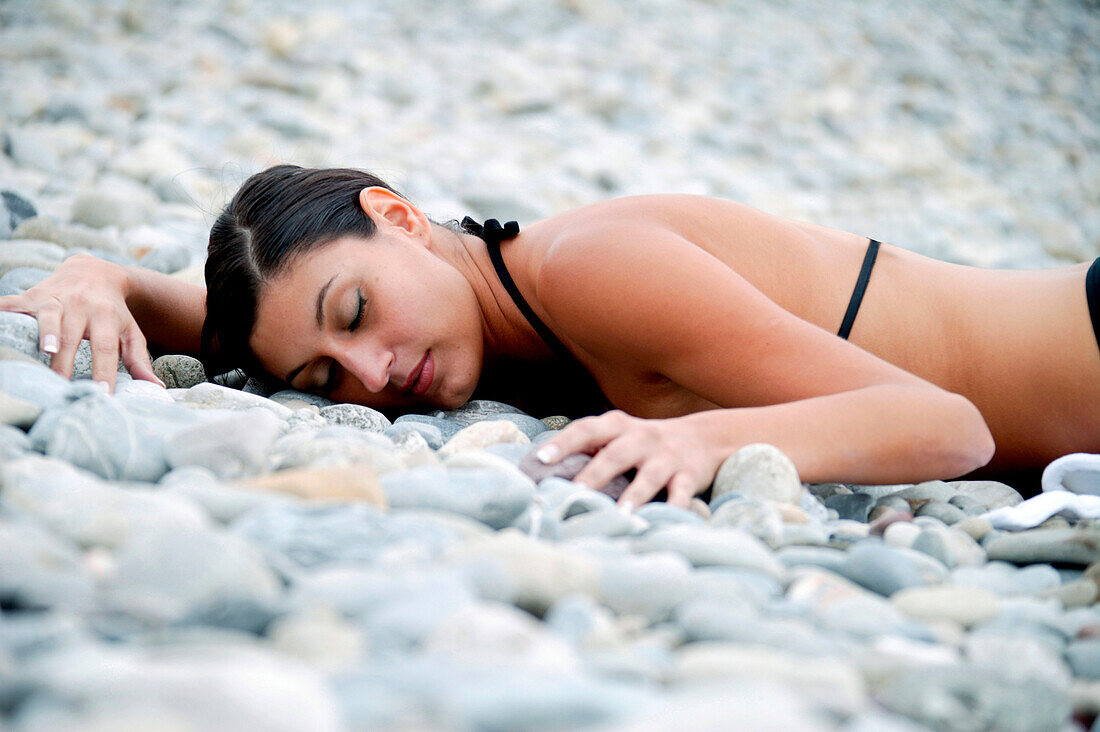 Young woman lying on pebble beach