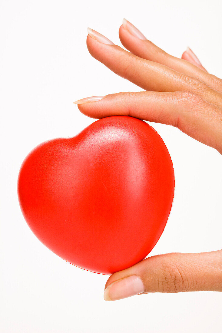 Woman's hand holding a red plastic heart