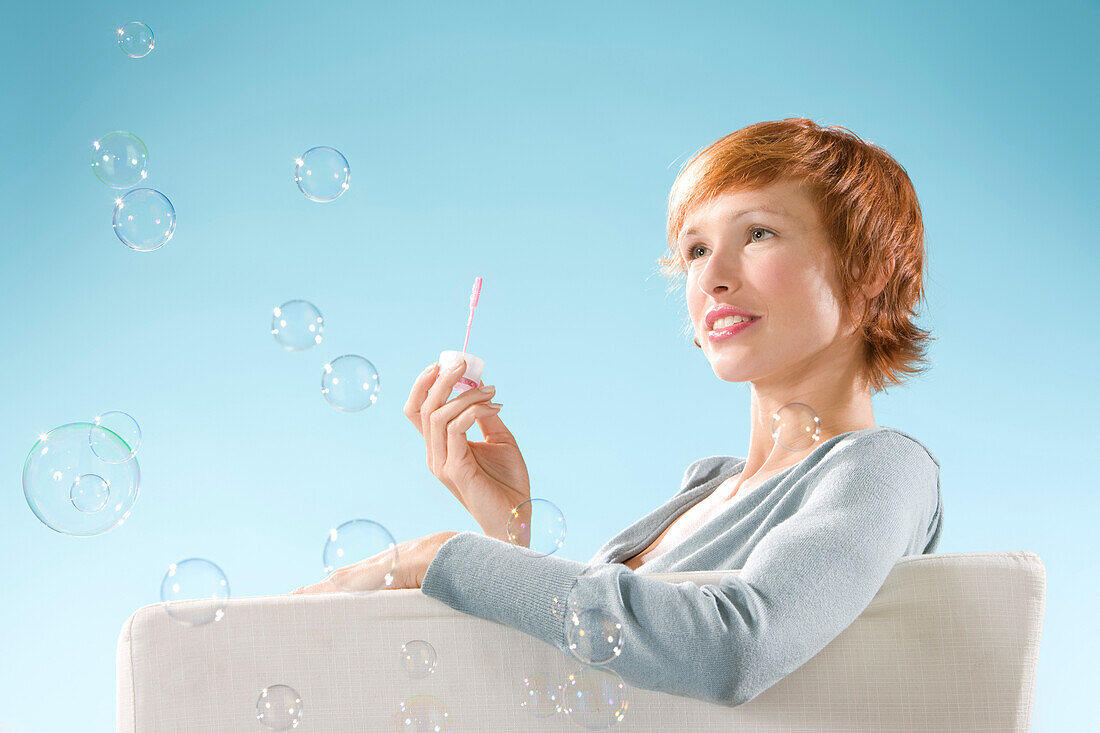 Claire portrait on light blue background, playing with bubbles