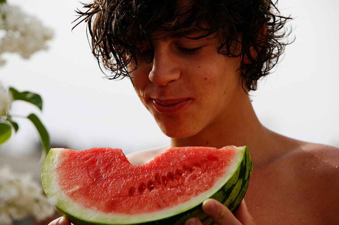 Portrait of a teen boy eating slice of watermelon