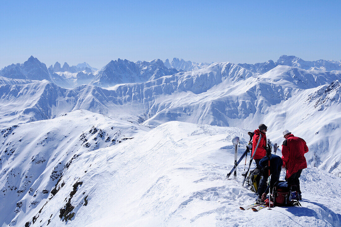 Group of backcountry skiers resting at summit, Dolomites in background, Kreuzspitze, Villgraten mountains, Hohe Tauern mountain range, East Tyrol, Austria