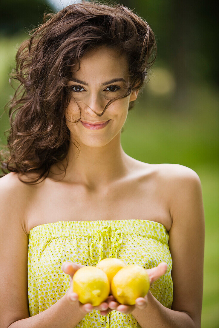Young woman holding three lemons