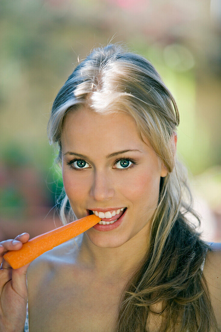 Portrait of a young woman eating a carrot