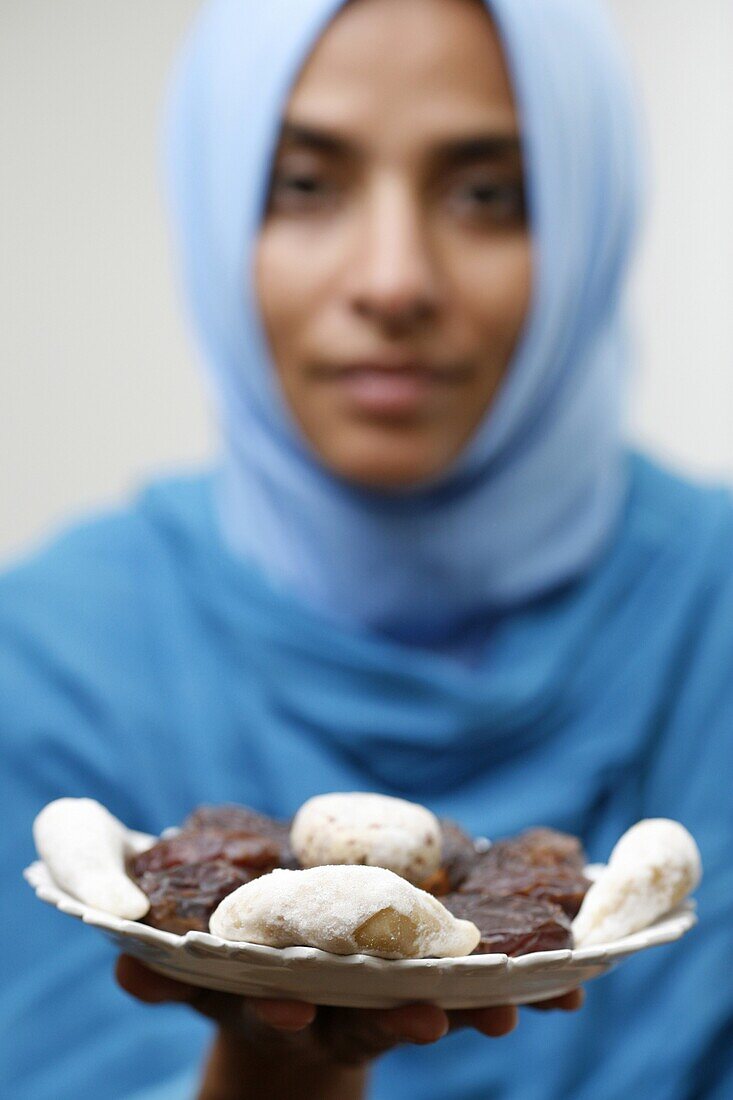 France, Paris, Muslim woman offering Ramadan pastries