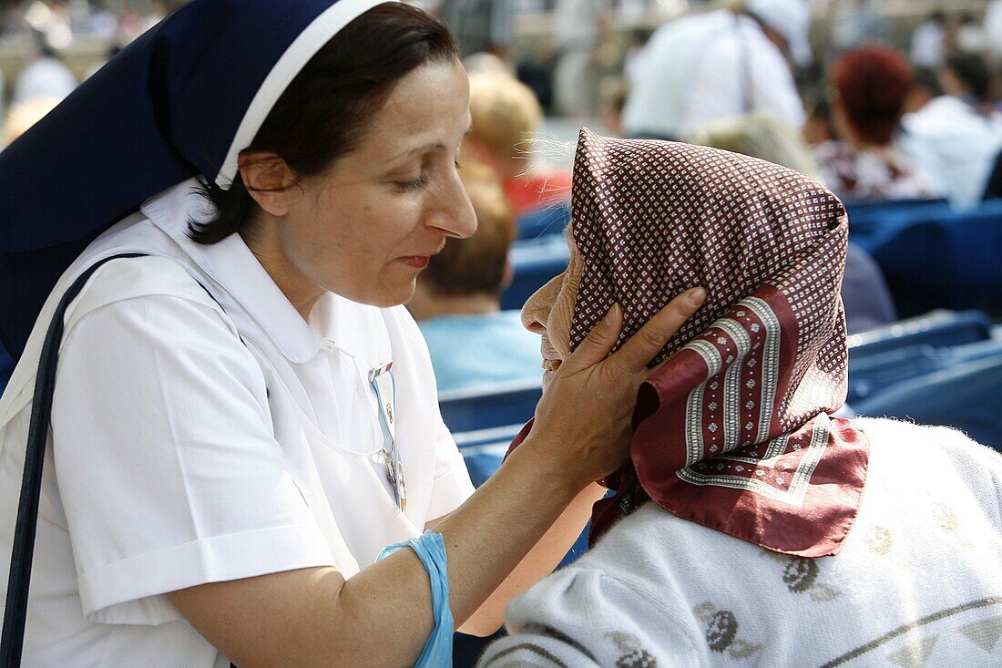 France, Lourdes, Volunteer holding a disabled person's face