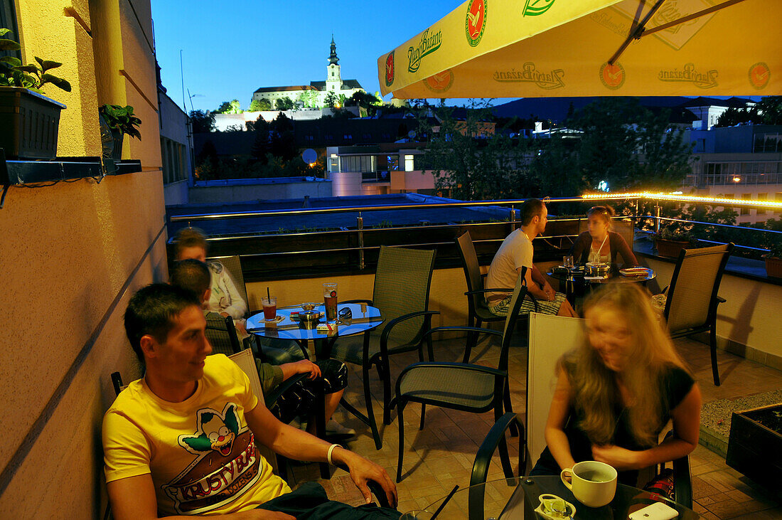 People at a cafe at Svaetoplukovo Square with cathedral in the evening, Nitra, western Slovakia, Europe