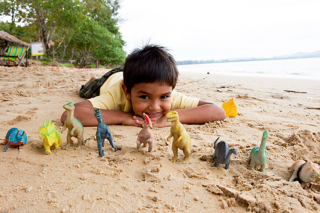 Thailändischer Junge am Strand mit seinen Dinos, Khao Lak, Andamanensee, Thailand