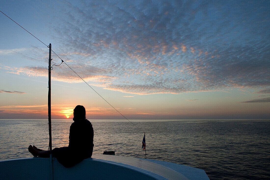 Tauchtouristin geniesst den Sonnenuntergang auf dem Tauchboot, Similan Inseln, Andamanensee, Thailand