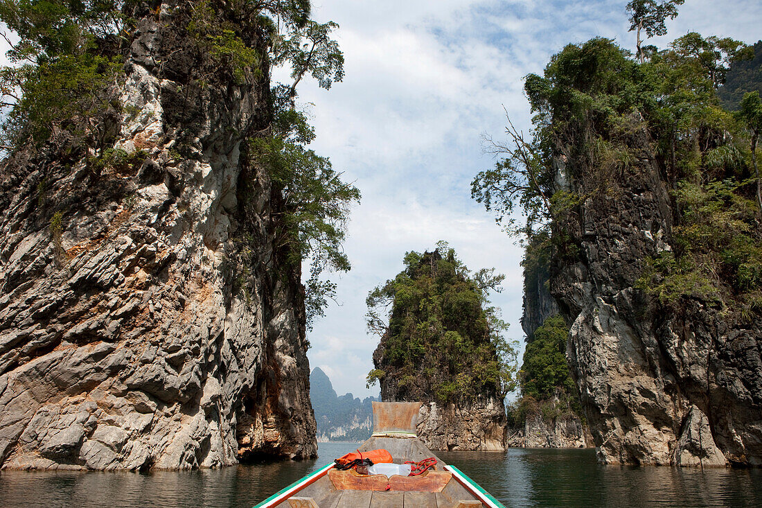 Long tail boat between limestone rocks on the Khao Sok National Park Reservoir Lake, Khao Sok National Park, Andaman Sea, Thailand