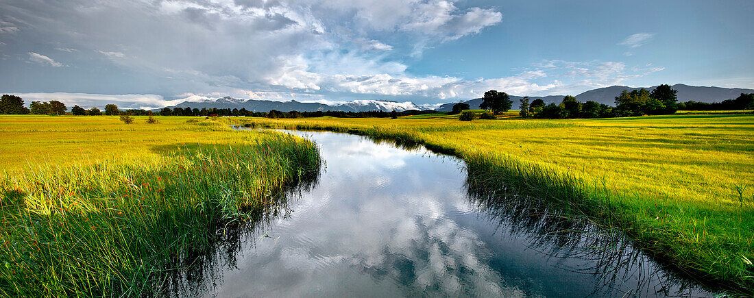 River Ach between fields, near Uffing, Herzogstand and Heimgarten in background, Ester mountains, Upper Bavaria, Germany