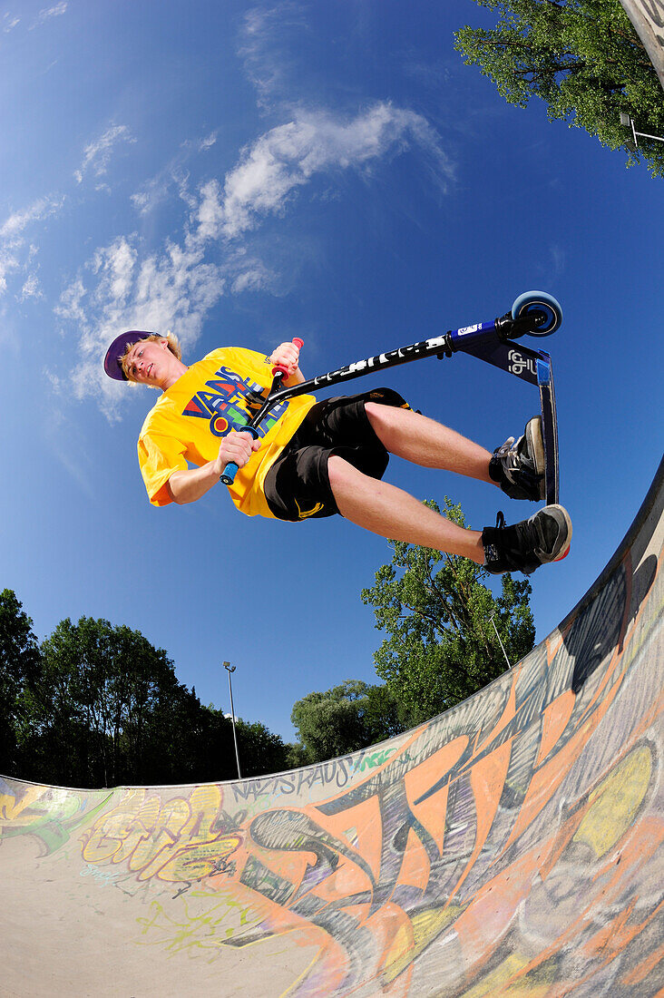 Young man performing jump with scooter, skatepark, Munich, Upper Bavaria, Germany