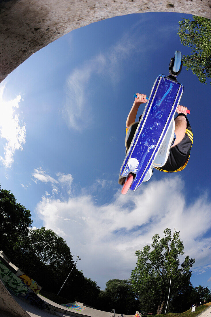 Junger Mann im Sprung mit einem Tretroller, Skatepark, München, Oberbayern, Bayern, Deutschland