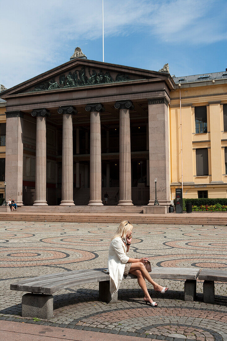 Frau sitzt auf Bank vor Nationalgalerie, Oslo, Südnorwegen, Norwegen