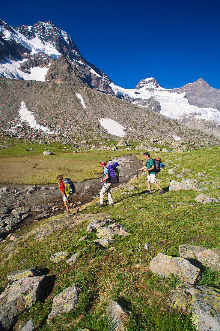 Three hikers near a stream, Breithorn and Tschingelhorn in background, Lauterbrunnen Valley, Canton of Bern, Switzerland