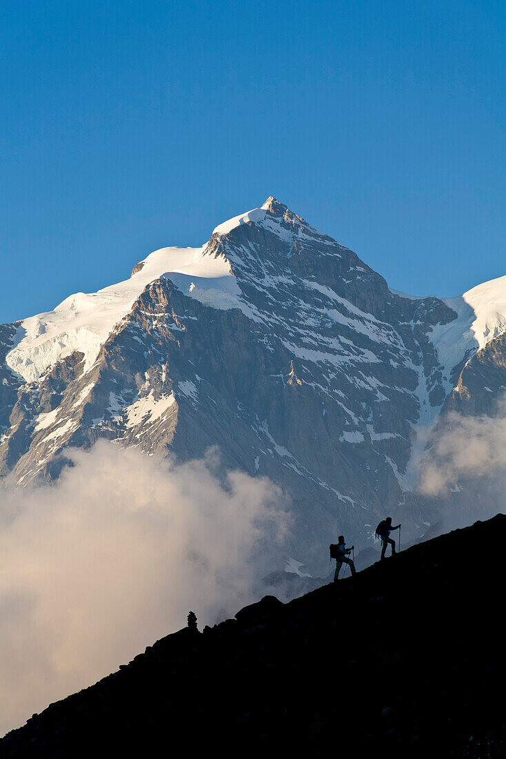 Two mountain hikers ascending, mount Jungfrau in backgound, Lauterbrunnen Valley, Canton of Bern, Switzerland