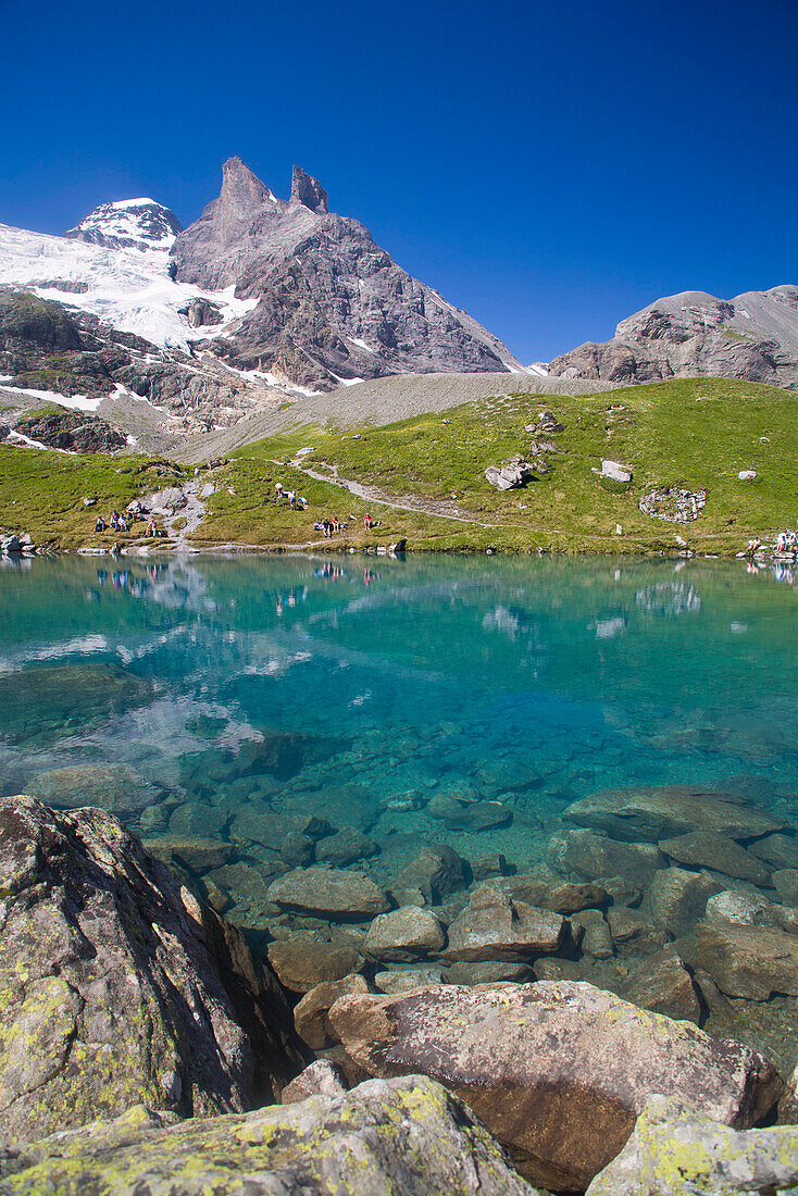 Hikers at Oberhorn Lake, Tschingelhorn and Breithorn Glacier in background, Lauterbrunnen Valley, Canton of Bern, Switzerland