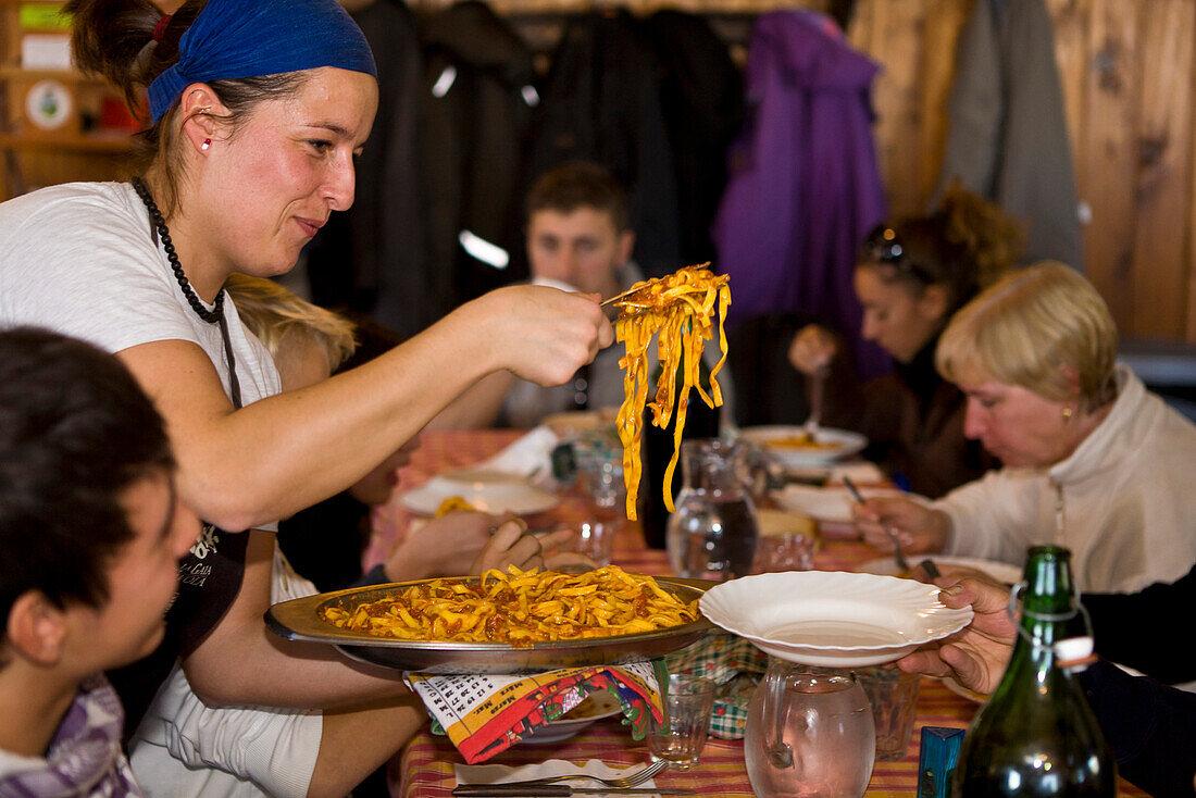 Woman serving pasta in mountain lodge Rifugio Agrituristico Salvin, Monastero di Lanzo, Piedmont, Italy