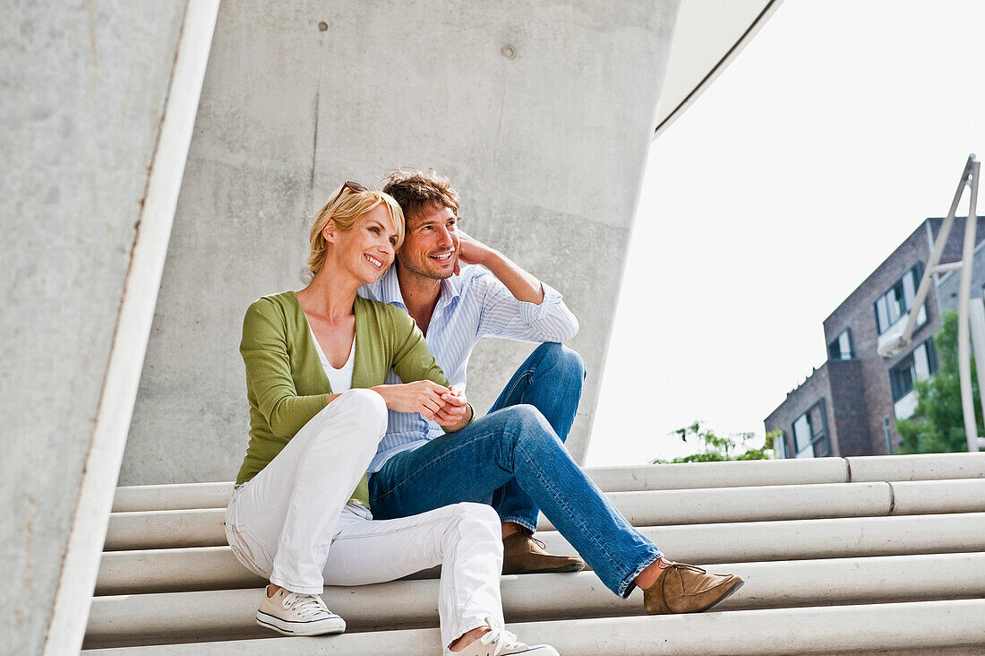 Couple sitting on staircase, HafenCity, Hamburg, Germany