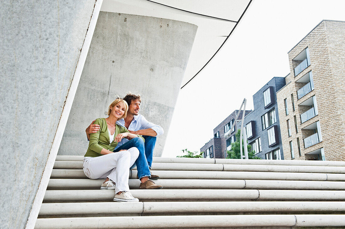 Couple sitting on staircase, HafenCity, Hamburg, Germany