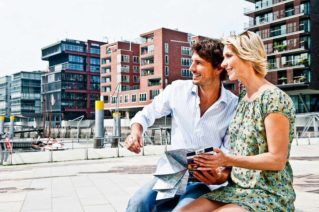 Couple holding a city map at Magellan-Terraces, HafenCity, Hamburg, Germany