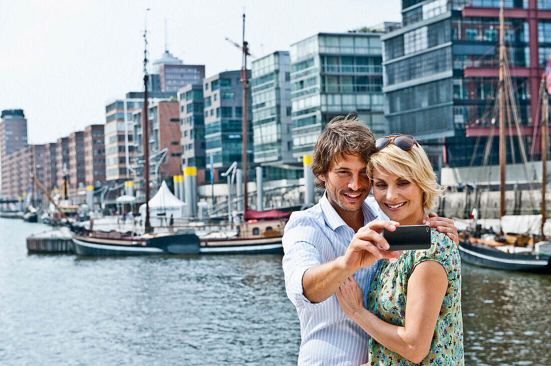 Couple taking photograph of themselves, Magellan-Terraces, HafenCity, Hamburg, Germany