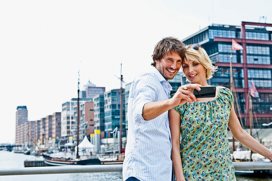 Couple taking photograph of themselves, Magellan-Terraces, HafenCity, Hamburg, Germany