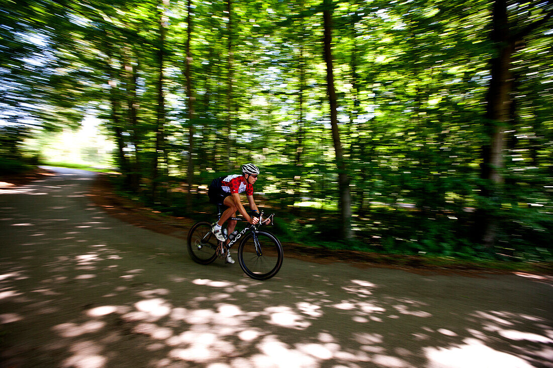 Man road cycling in forest, Bergisches Land, North Rhine-Westphalia, Germany