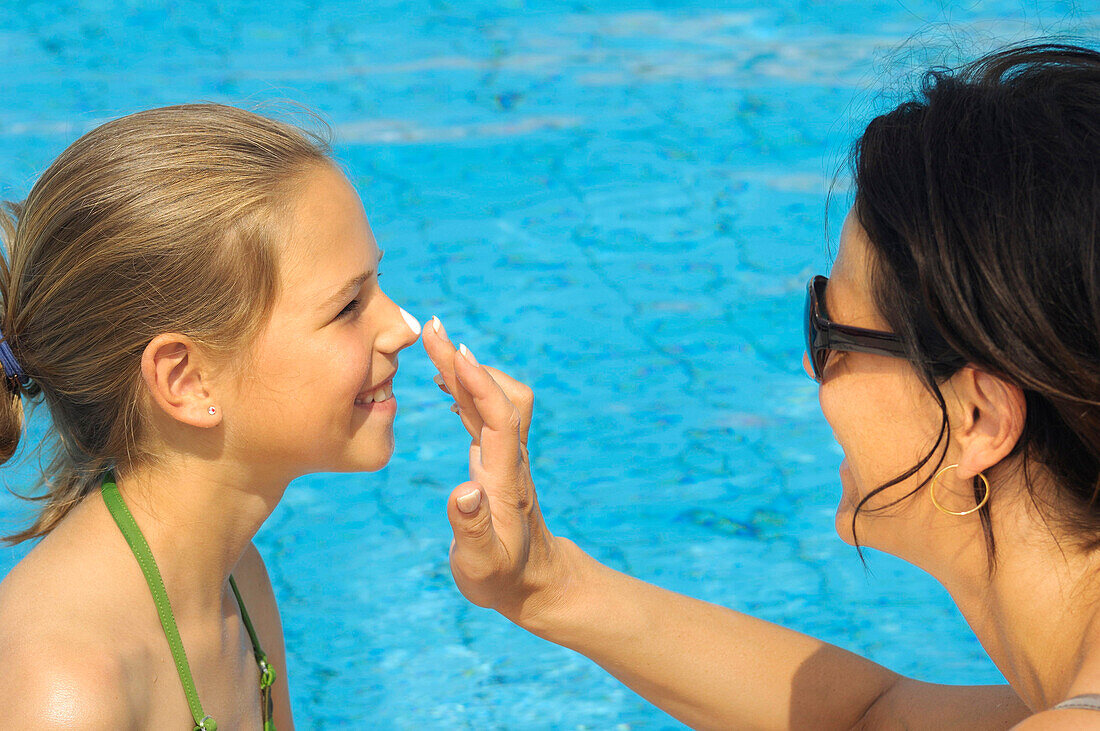 Mother applying sun cream on her daughter's face