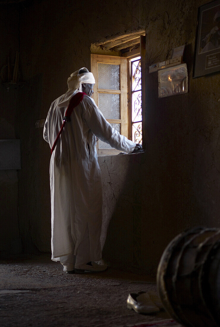 Gnawa Musician in White Robe Looking out Window, Khemlia, Morocco