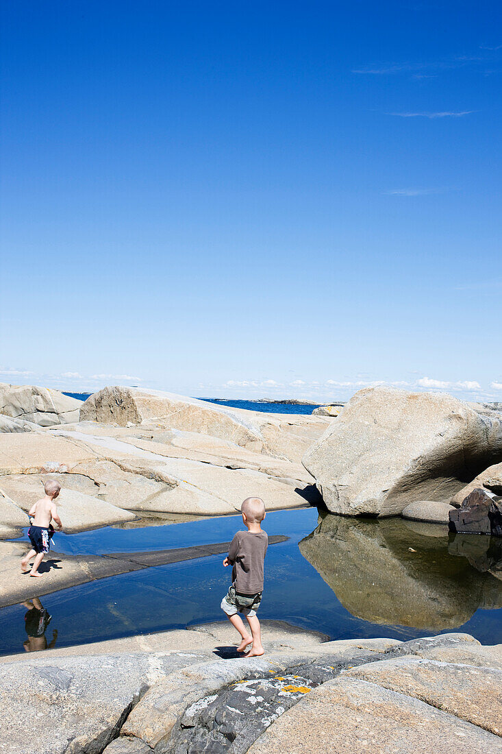 Two Young Boys Playing in Tidal Pool Along Rocky West Coast, Sweden