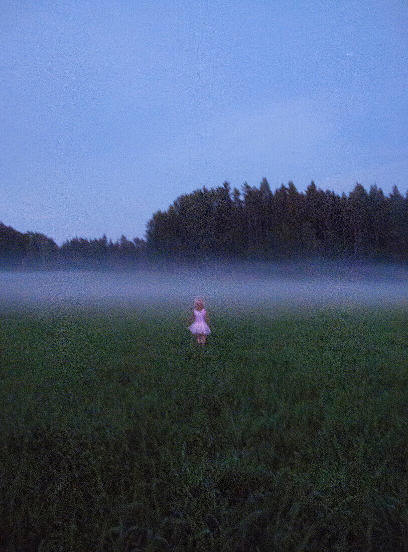Young Blonde Girl in Pink Dress in Misty Field
