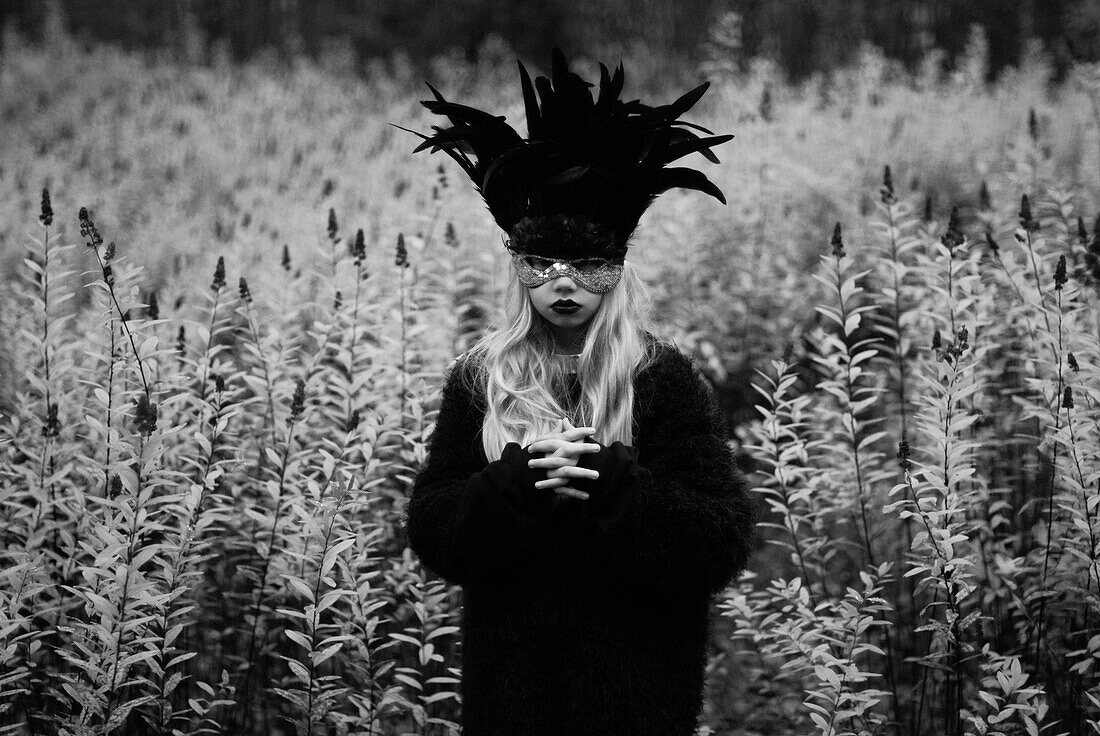 Girl With Long Blonde Hair Wearing Feathered Mask in Field of Wildflowers