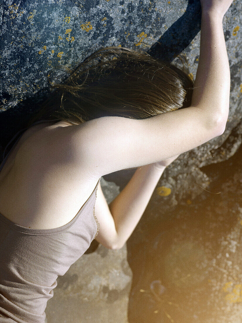 Woman Leaning Against Rock With Arm Covering Face