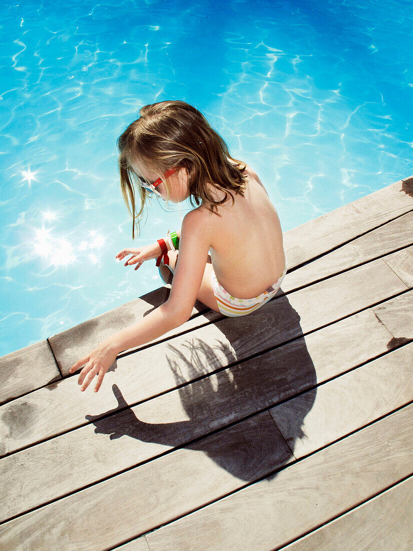 Young Girl Sitting at Edge of Swimming Pool