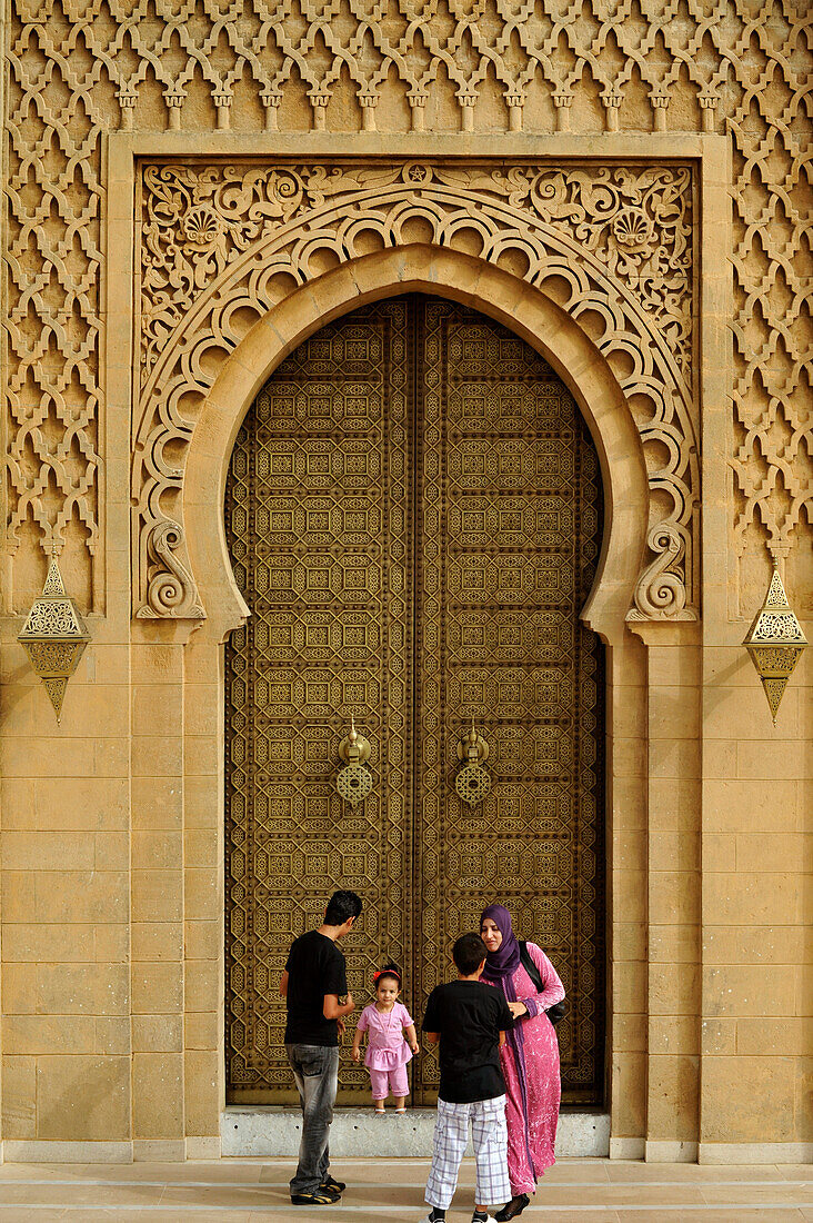 Family in front of an adorned door of the mosque at the mausoleum of Mohammed V, Rabat, Morocco