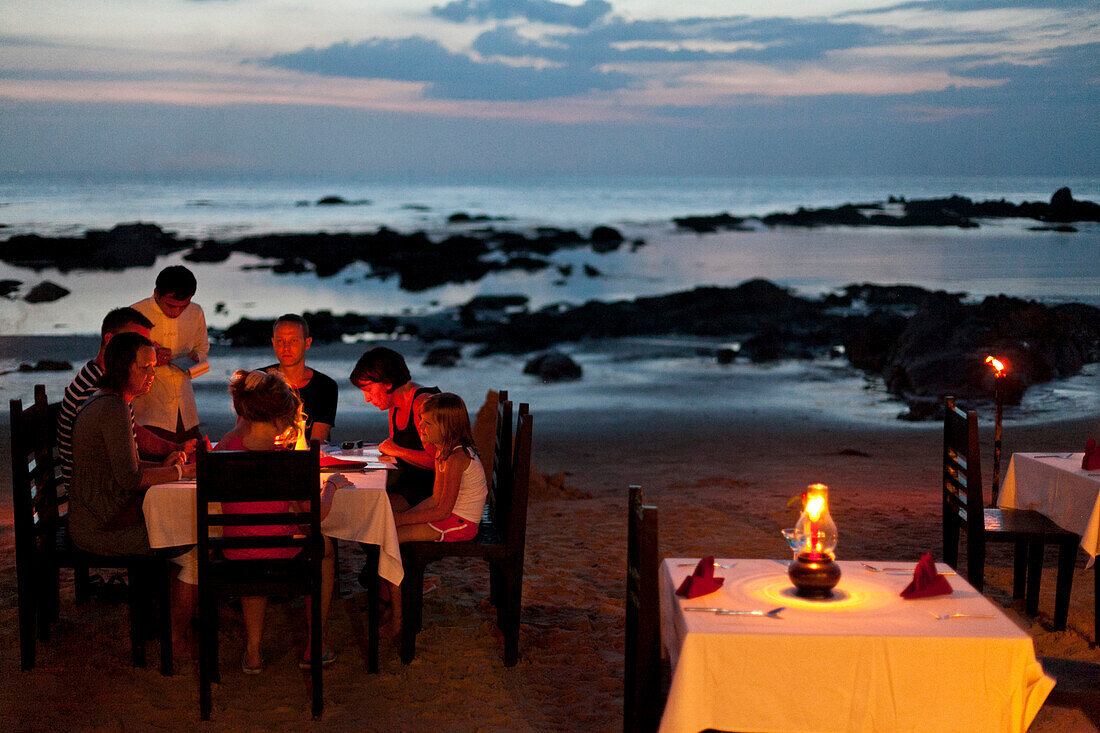 Familie beim Abendessen am Strand in der Abenddämmerung, Restaurant Indigo, Andamanensee, Indischer Ozean, Khao Lak, Thailand, Asien