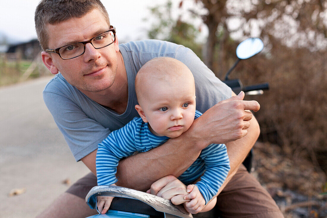 Father and son sitting on a moped, Pai, Thailand, Asia